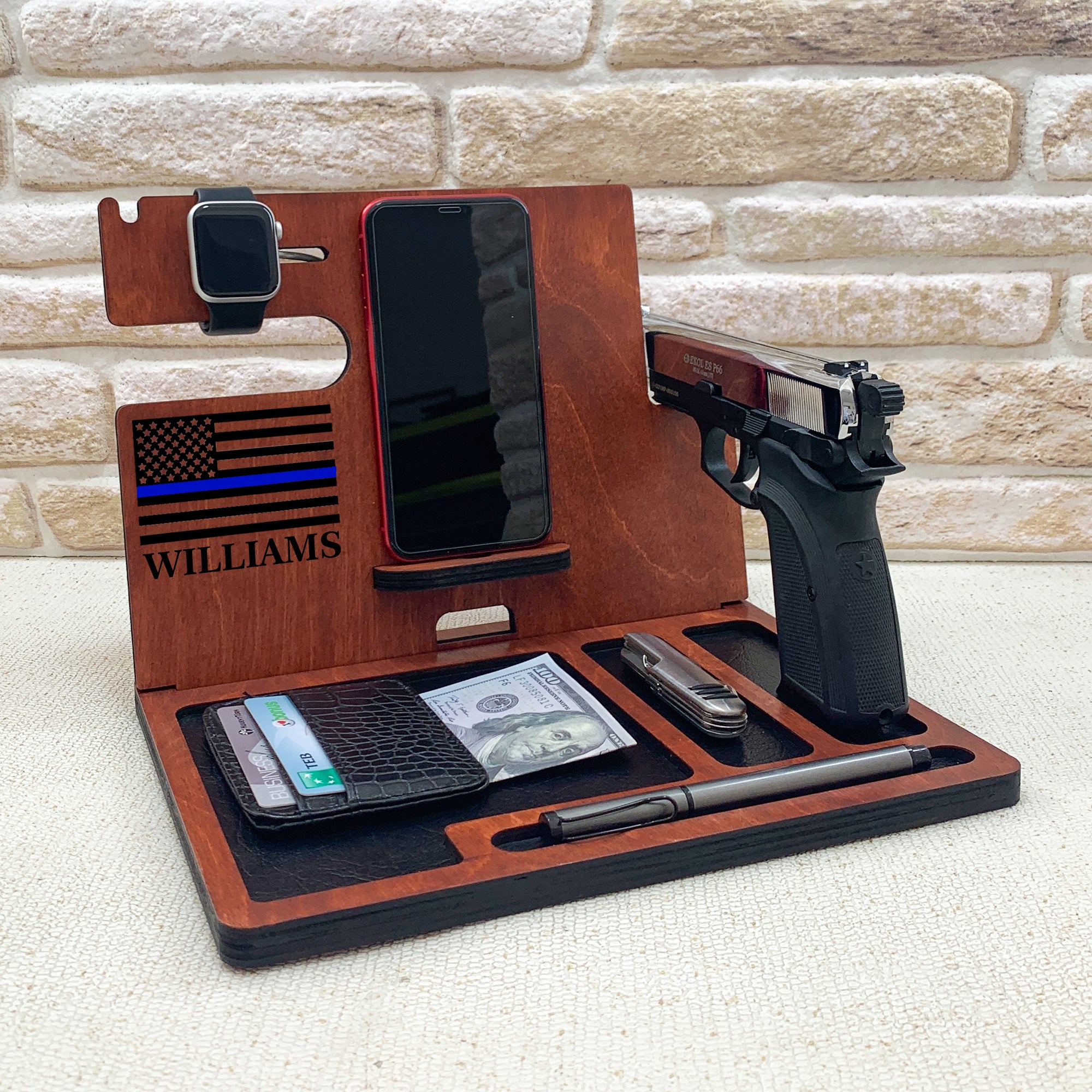 Personalized wooden nightstand valet with custom engraved thing blue line flag with batch number. Personalized gifts for police officer which include holders for an Apple Watch, smartphone, wallet, pen, and a dedicated slot for a handgun. The stand is organized to keep everyday carry items neatly in place. ideal gifts for law enforcement, police retirement and the one who have gun.